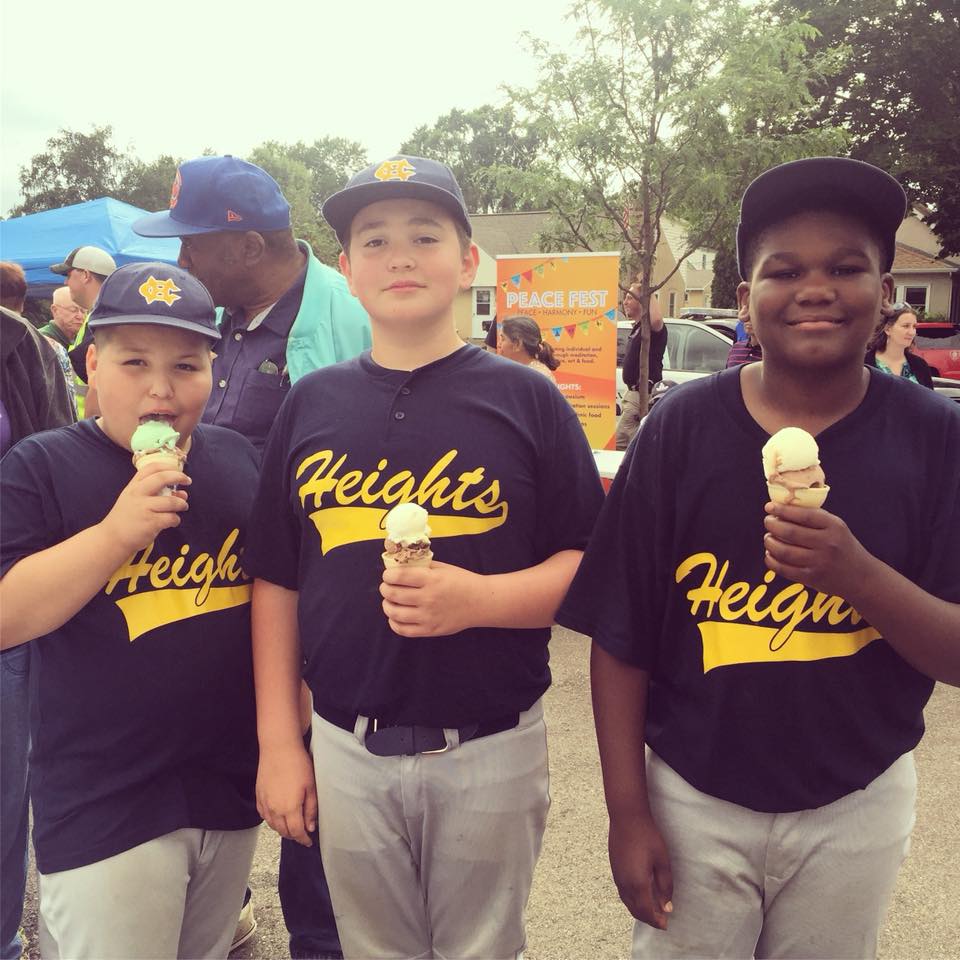3 kids in baseball uniforms enjoy ice cream.