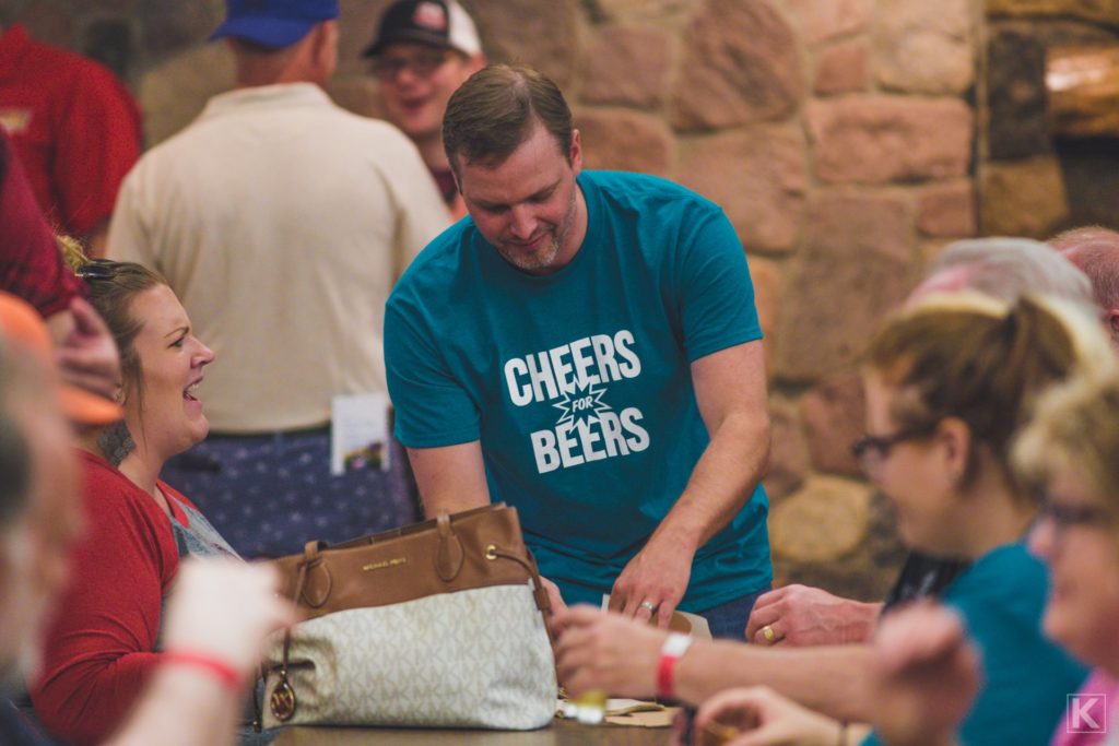 A volunteer helps bus tables at a beer tasting event.
