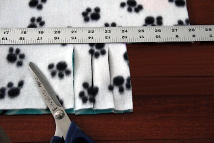 Scissors cutting 1 inch fringe strips into fleece fabric