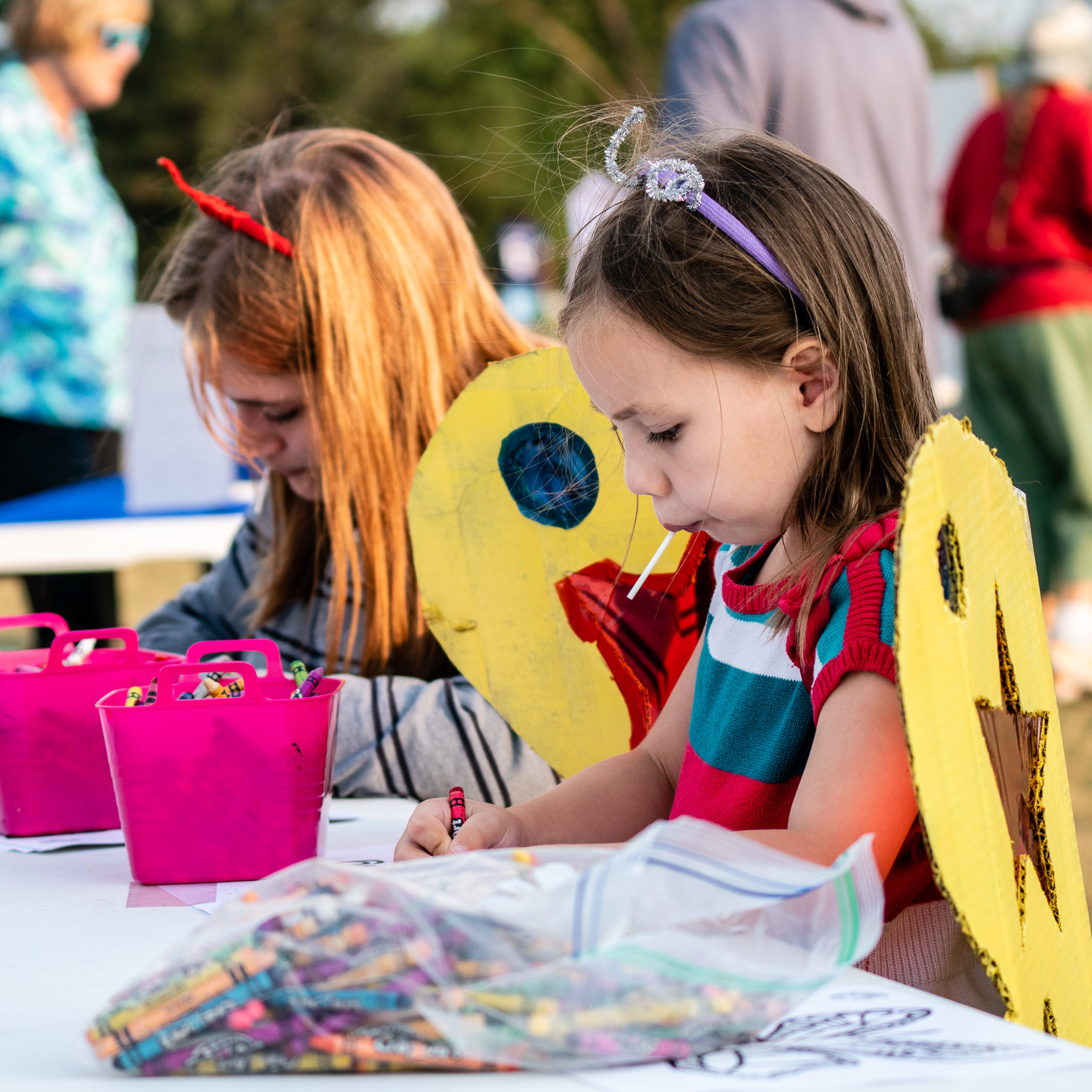 Kids in butterfly costumes do a coloring activity at the 2021 Monarch Festival in Columbia Heights, MN