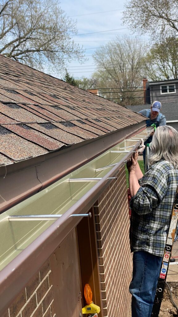 Volunteers at the Blooming Sunshine food forest in Columbia Heights install rain gutters on the Łomianki Park building.
