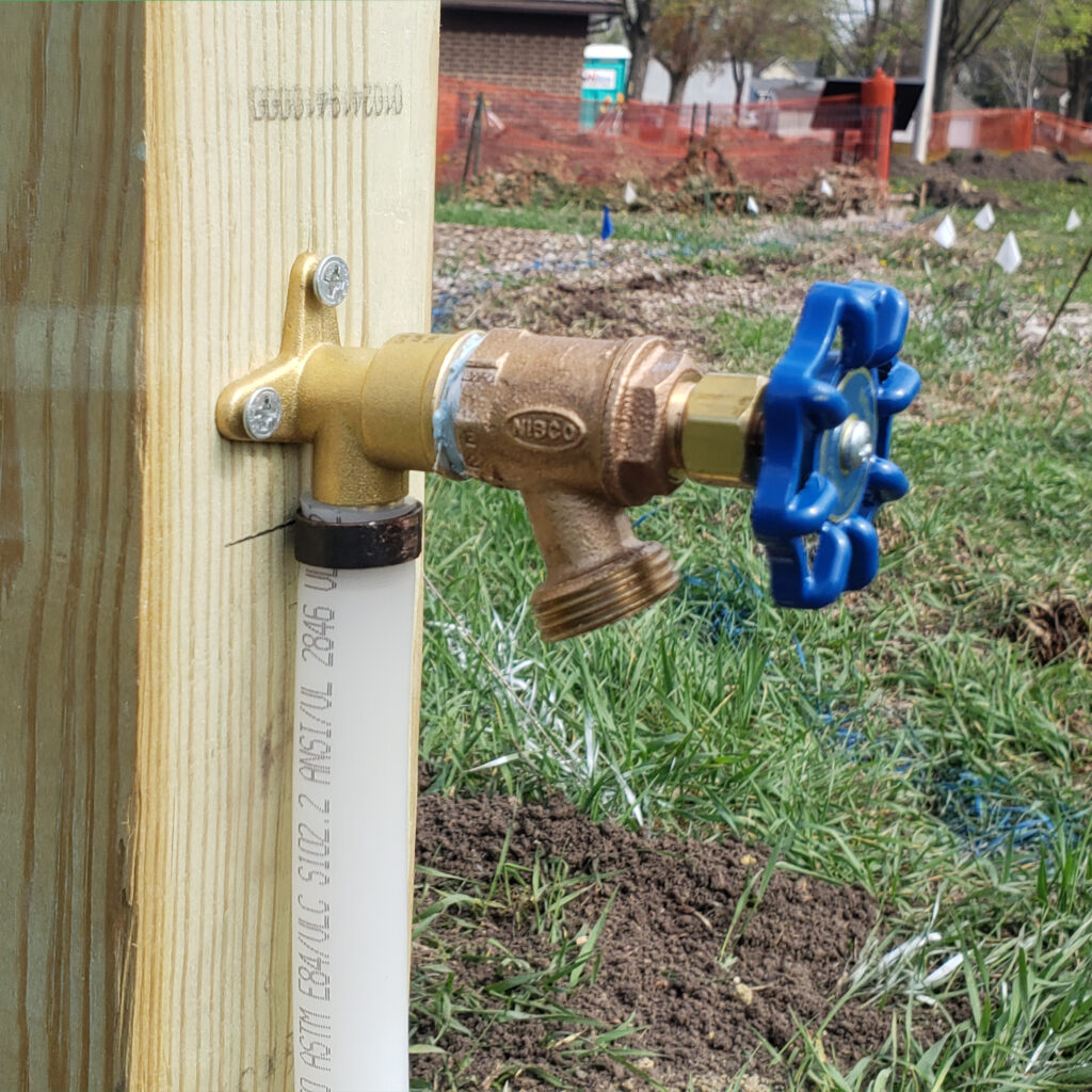 A water spigot is mounted on a post in the garden.