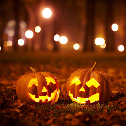 Two lit jack-o'-lanterns in a park at night